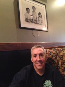 Kevin Ryan, owner of Gov Stumpy's. Sitting beneath a picture of his kids!